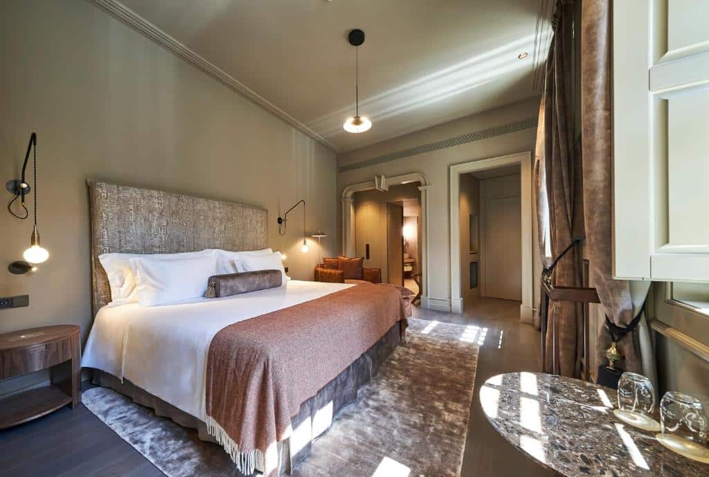 Quarto amplo do PortoBay Flores com cama de casal do lado esquerdo e uma mesa do lado direito. Representa hotéis bem localizados no Porto.