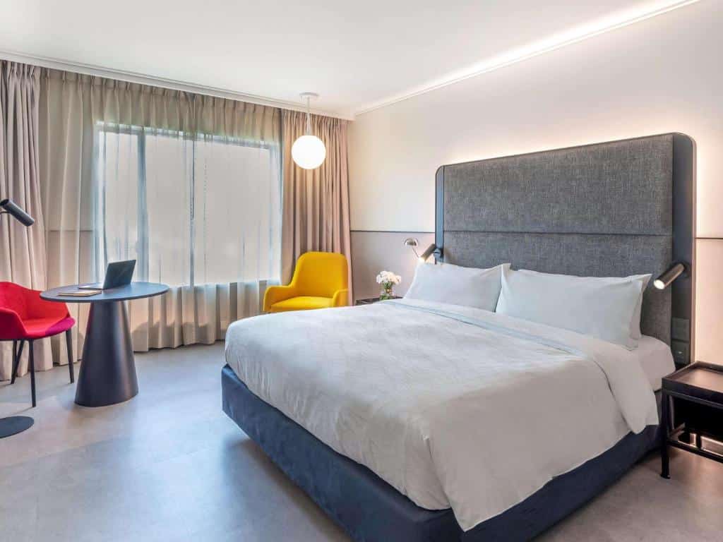 Quarto do Pullman Santiago Vitacura com cama de casal do lado direito, uma poltrona amarela do lado esquerdo. Representa hotéis Mercure em Santiago.
