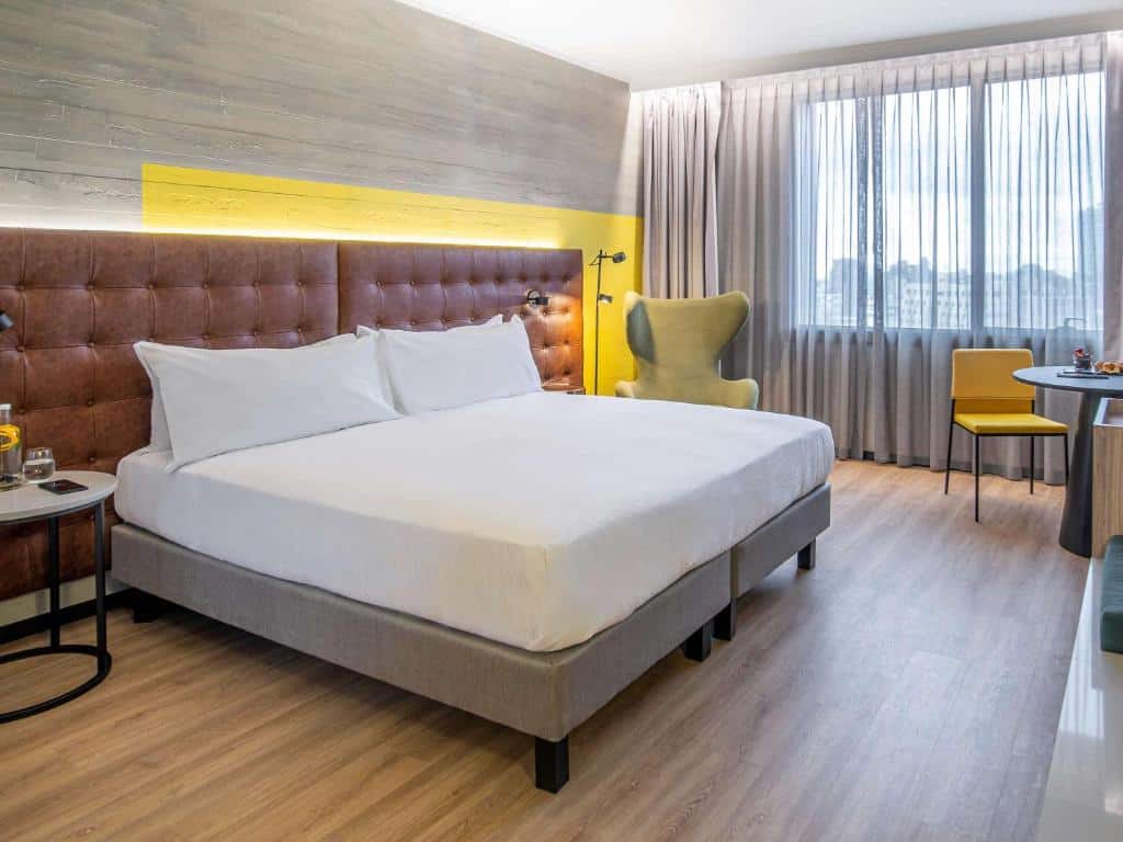 Quarto do Pullman Santiago El Bosque com cama de casal do lado esquerdo e uma poltrona verde clara do lado esquerdo da cama. Representa hotéis Mercure em Santiago.