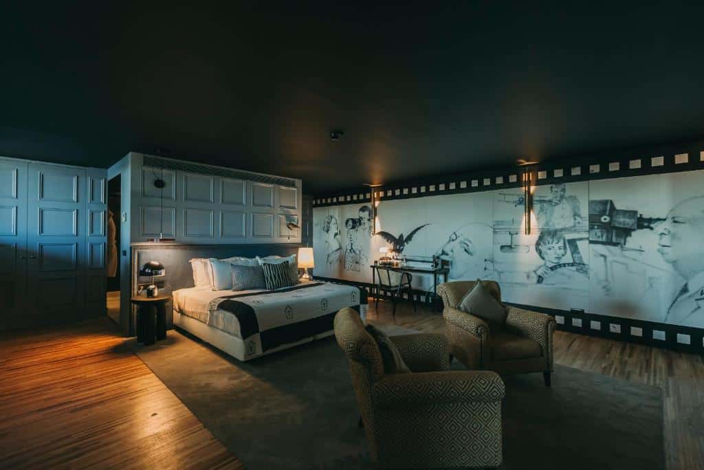 Quarto do Torel Avantgarde ambiente amplo e requintado com cama no centro, com duas cômodas ao lado com luminária e a frente a cama duas poltronas. Representa hotéis de luxo no Porto.