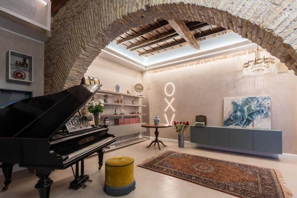 recepção do Poēsis Experience Hotel, com piano, teto de madeira com arcos em pedra e luminárias estilosas, há, ainda, prateleiras abertas com decorações