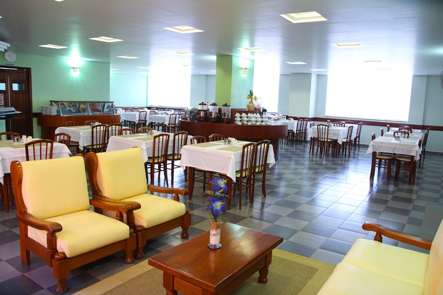 Parte interna do hotel com várias mesas e cadeiras para comer e são quadriculado, ilustrando post Hotéis em Barretos.