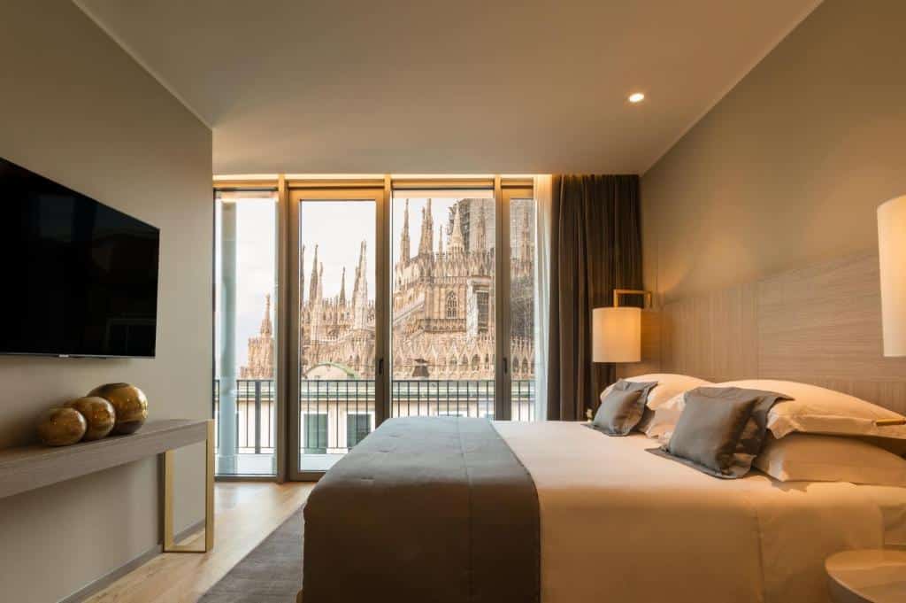 Quarto do Rosa Grand Milano - Starhotels Collezione com uma varanda ampla com vista para a Catedral de Milão, uma cama de casal, uma cabeceira com duas luminárias e uma televisão de frente para a cama, para representar hotéis perto do Duomo em Milão