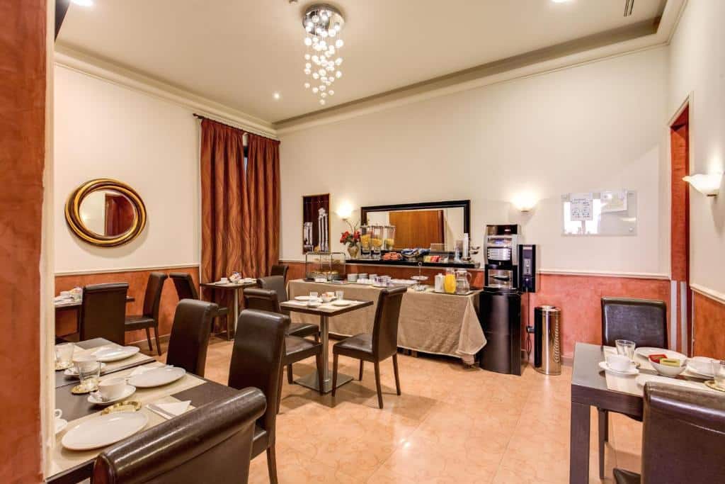 salão do Hotel Everest Inn Rome com mesas e cadeiras de madeira, com uma bancada com alimentos e um lustre acima