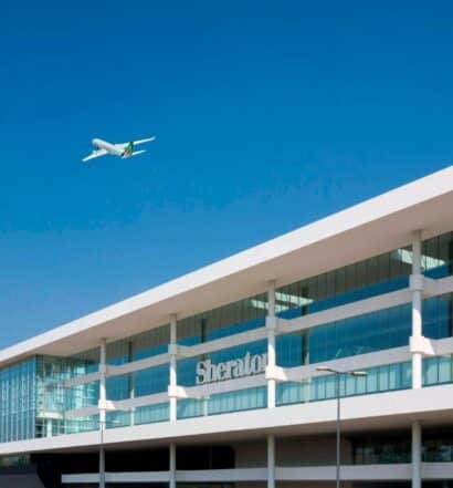 Fachada do Sheraton Milan Malpensa Airport Hotel & Conference Centre com um avião passando em cima da propriedade