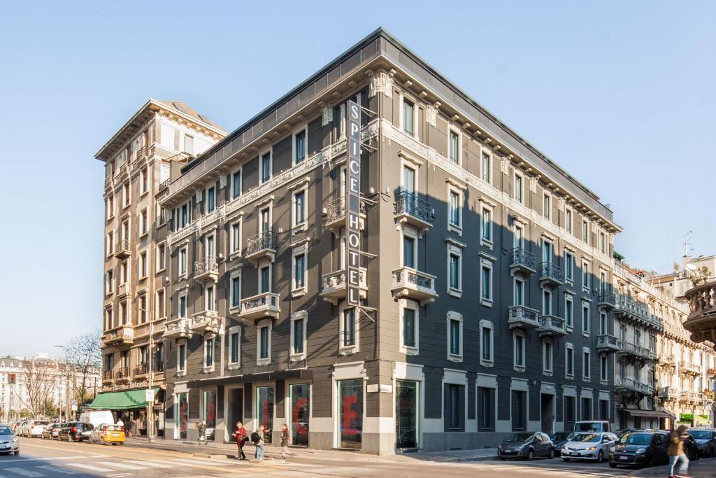 Prédio do Spice Hotel Milano com cinco andares, diversas sacadas, pintado em cinza e branco com uma arquitetura clássica e antiga, para representar hotéis perto da Estação Central em Milão