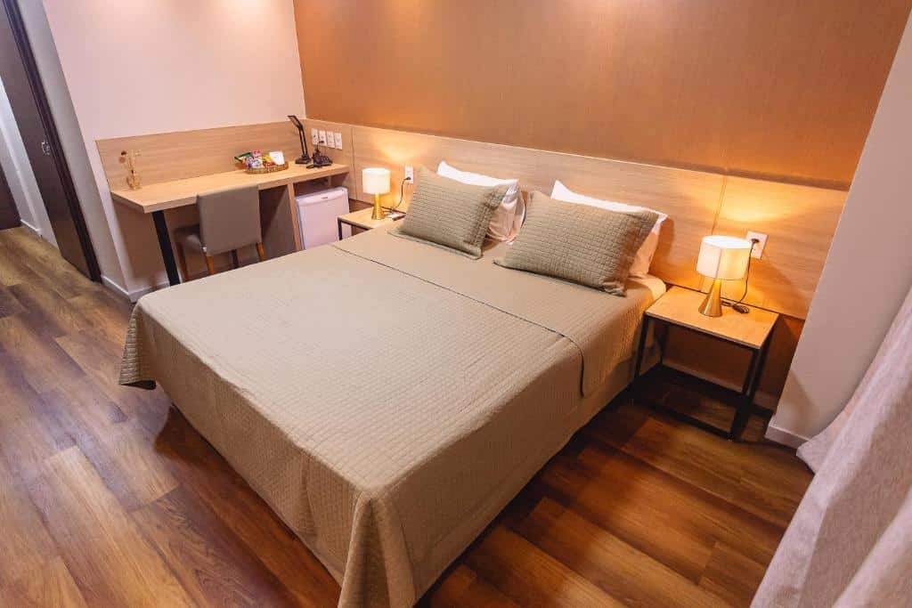 Quarto com parede marrom claro, decoração em madeira, mesa com cadeira e luminárias ao lado da cama de casal. Imagem para ilustrar o post hotéis em Teresina.