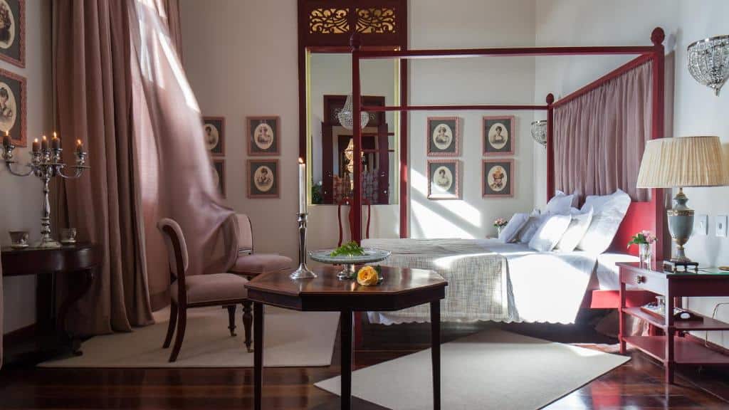 Quarto de hotel com decoração que remete a um quarto colonial. Cama de casal, móveis em madeira escura e quadros de época. Imagem para ilustrar o post hotéis em Parnaíba.