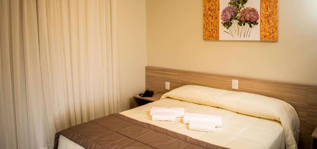 suíte do sky serra hotel mostrando uma cama de casal e um quadro de hortênsias pendurado acima da cabeceira