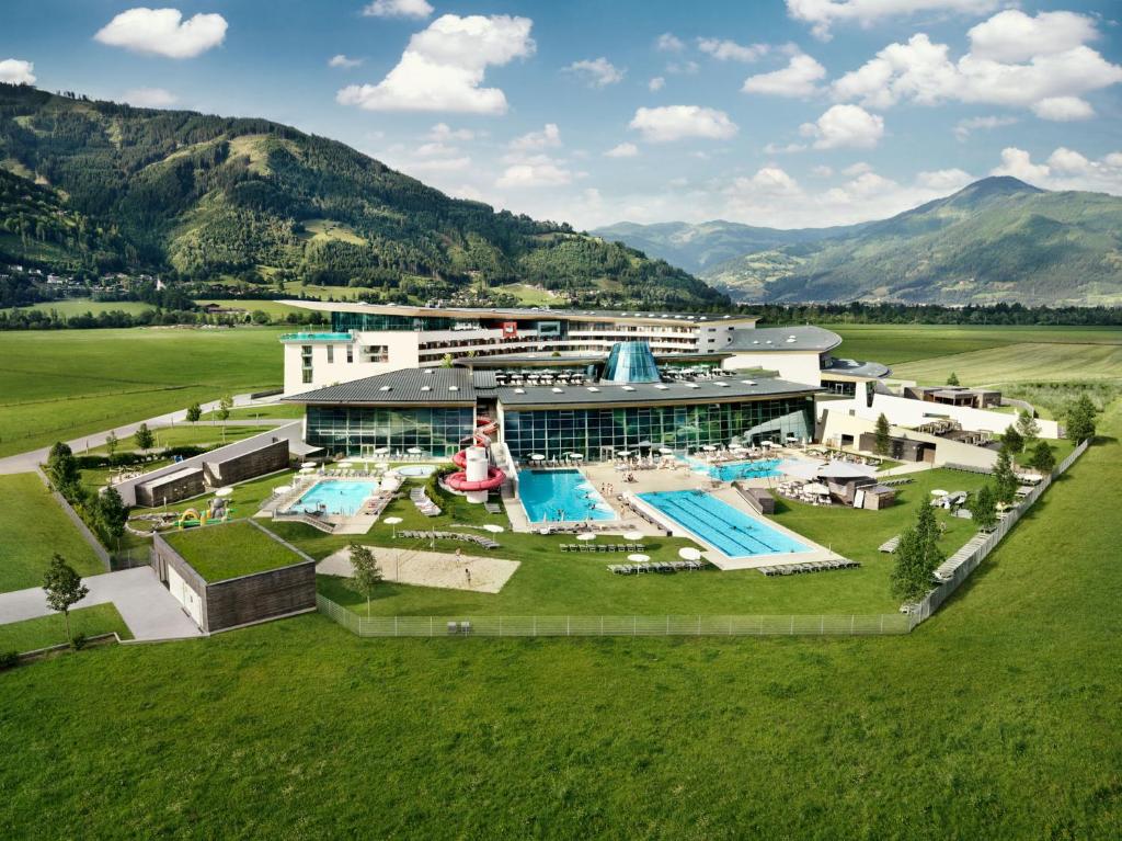 Imagem aérea de uma enorme construção com várias piscina e em volta um grande gramado verde durante o dia, ilustrando Hotéis em Salzburg.