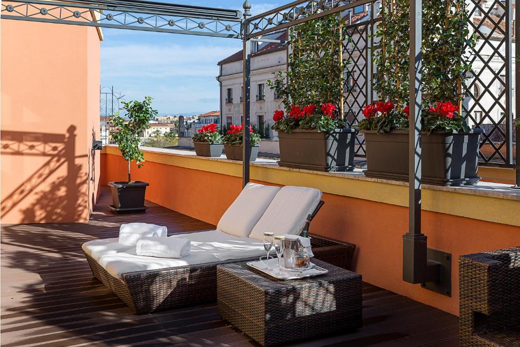 terraço do Baglioni Hotel Regina com flores vermelhas e vista para a cidade, há espreguiçadeiras e um apoio para bebidas onde é possível relaxar