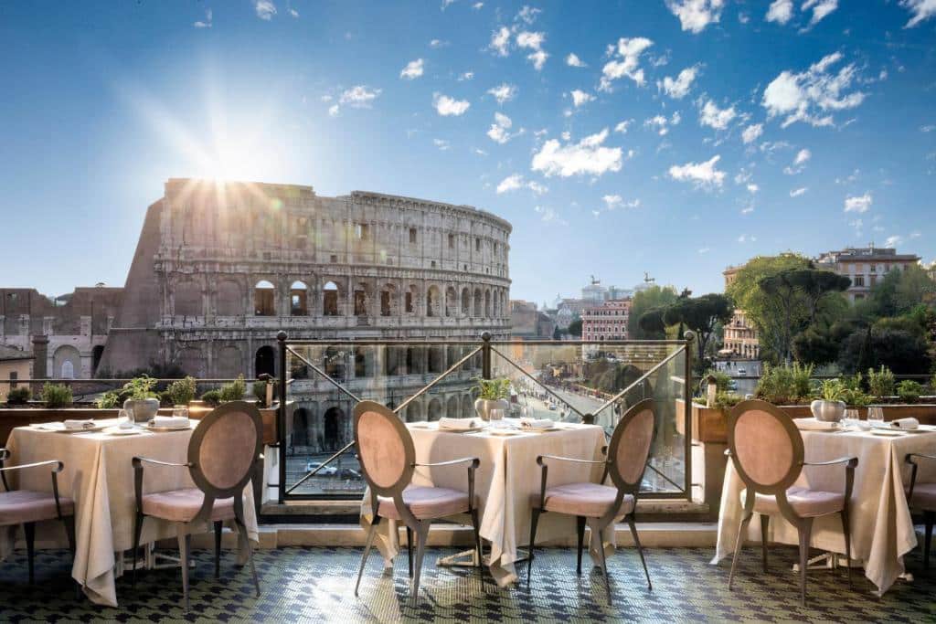 terraço com mesas e cadeiras no Hotel Palazzo Manfredi, com vista direta para o Coliseu
