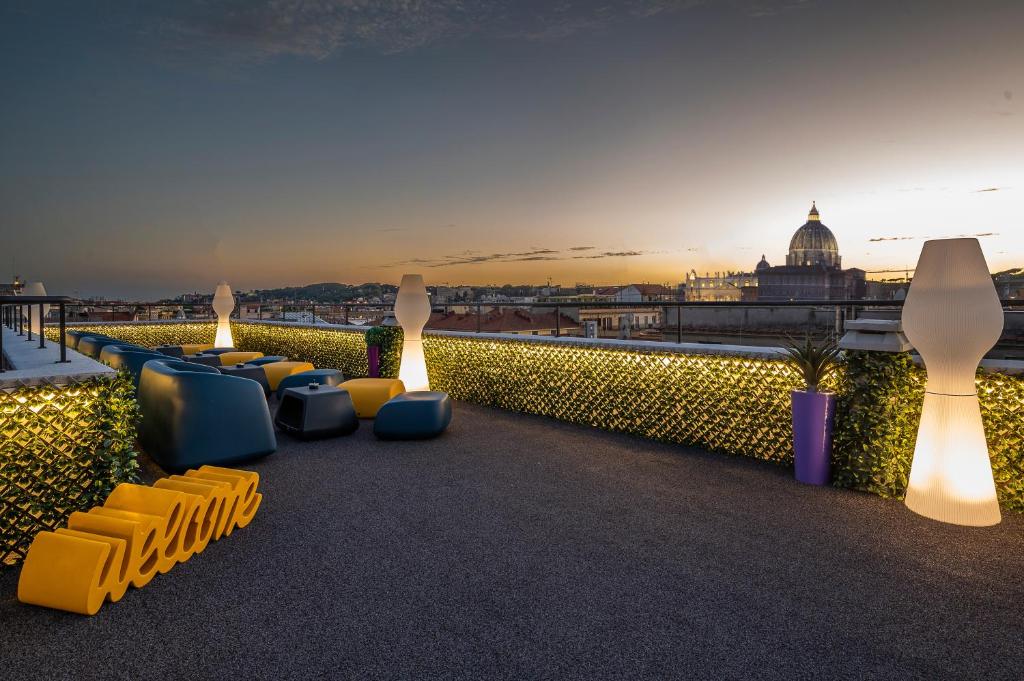 terraço do Hotel Relais Dei Papi com um ambiente aberto, há plantinhas e velas que parecem velas gigantes, poltronas e mesinhas em estilo moderna com vista para o Vaticano