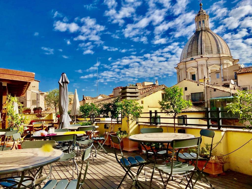 terraço do Navona Residenza de Charme com mesas e cadeiras de ferro com vista para monumentos históricos e céu azul