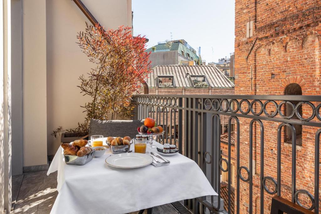 Terraço do Speronari Suites com uma mesa quadrada com itens de cama da manhã, uma cadeira estofada, e há também um vaso de plantas, para representar os melhores hotéis em Milão