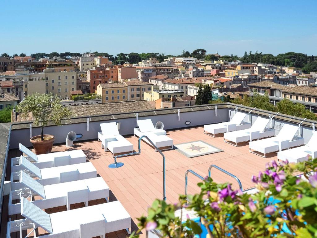 terraço com vista da cidade com piscina e espreguiçadeiras brancos do Mercure Roma Centro Colosseo