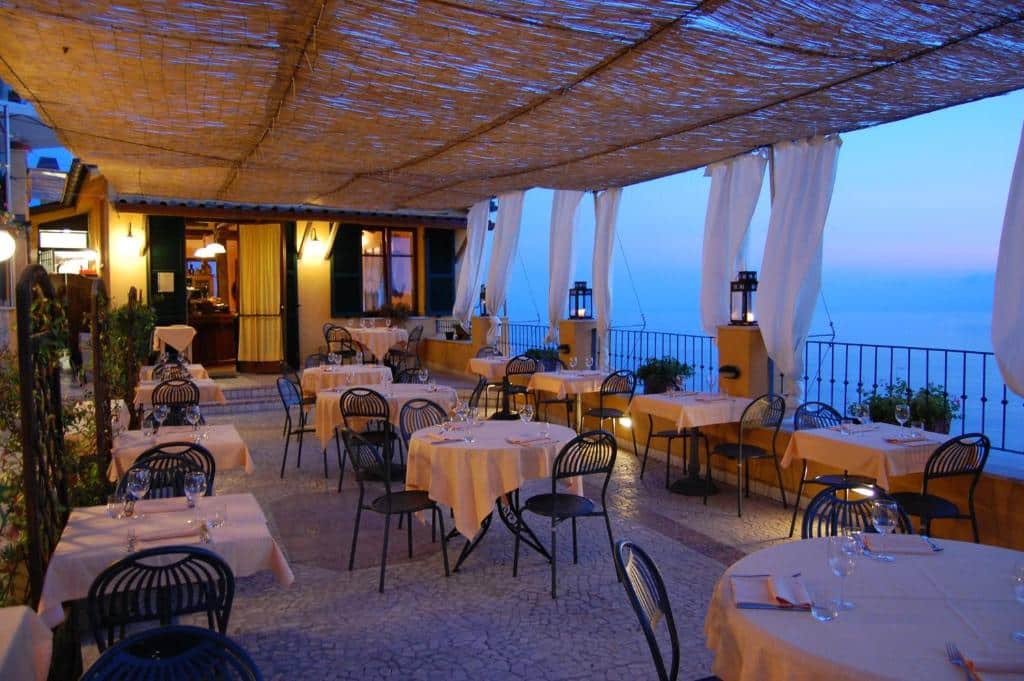 Parte do hotel com várias mesas e cadeiras para comer com vista para o mar da cidade, ilustrando post Hotéis em Cinque Terre.