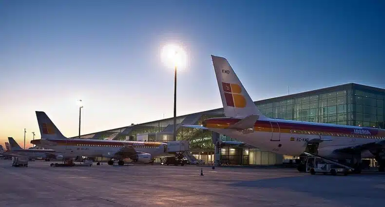 Dois aviões no terminal do aeroporto para ilustrar o post sobre aluguel de carro no aeroporto de Barcelona. O céu está azulado no final da tarde. - Foto: Iberia Airlines via Wikimedia Commons