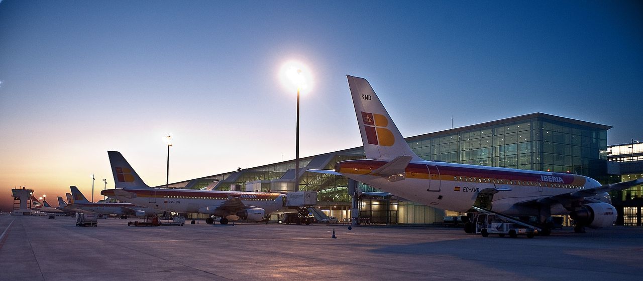 Dois aviões no terminal do aeroporto para ilustrar o post sobre aluguel de carro no aeroporto de Barcelona. O céu está azulado no final da tarde. - Foto: Iberia Airlines via Wikimedia Commons
