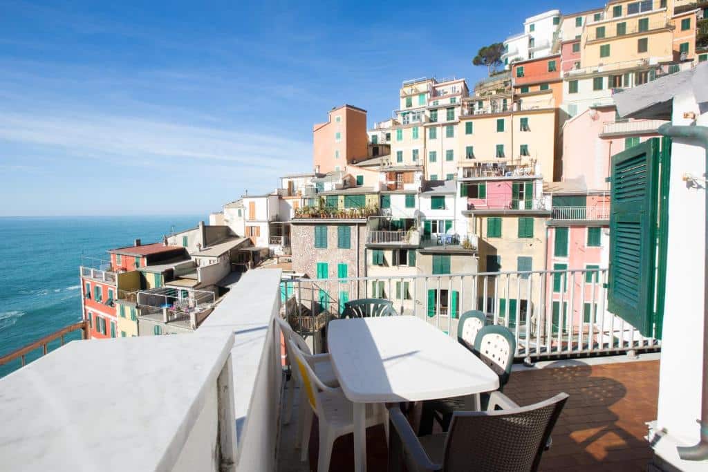 Sacada do hotel com uma mesa branca e algumas cadeiras em volta com vista para as construções da cidade e o mar azul, ilustrando post Hotéis em Cinque Terre.