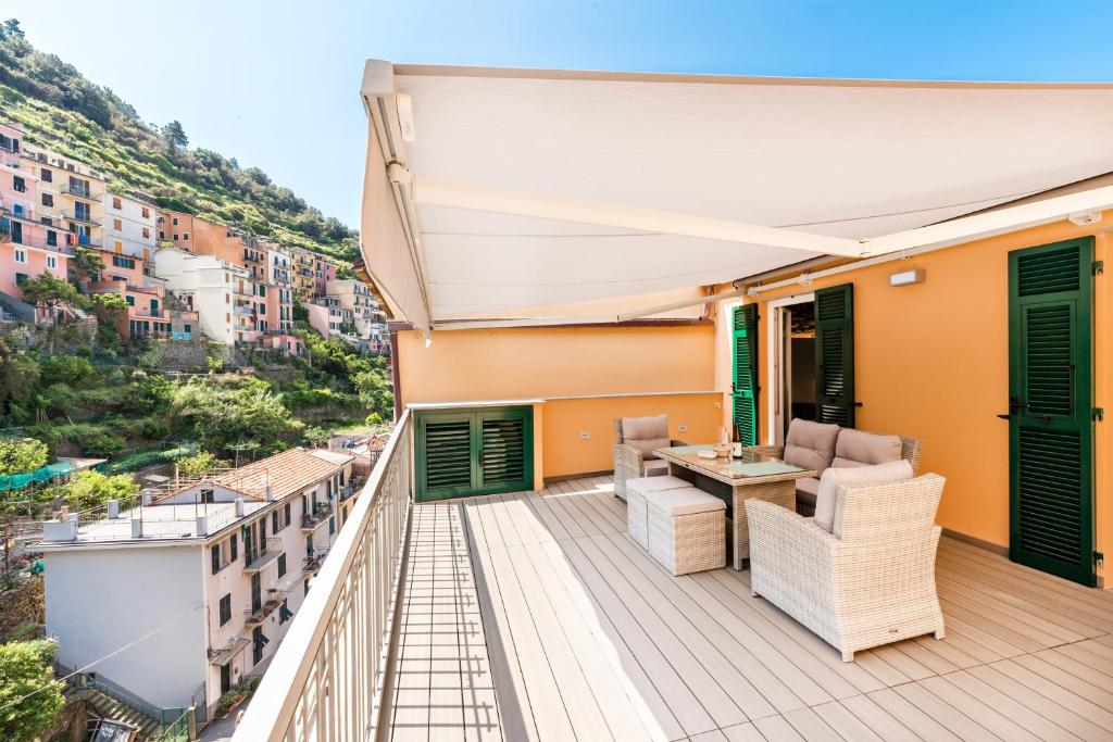 Varanda de um dos quartos do hotel com paredes amarelas, portas verdes, mesa e poltronas, cobertura branca e vista para as casas e montanhas, ilustrando post Hotéis em Cinque Terre.