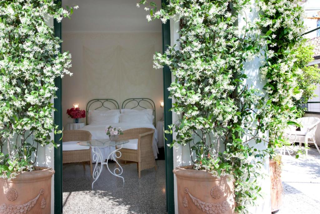 Quarto do Antica Locanda Dei Mercanti com uma porta que leva para um terraço com vasos de plantas, dentro há uma cama de casal, uma pequena mesa com duas cadeiras