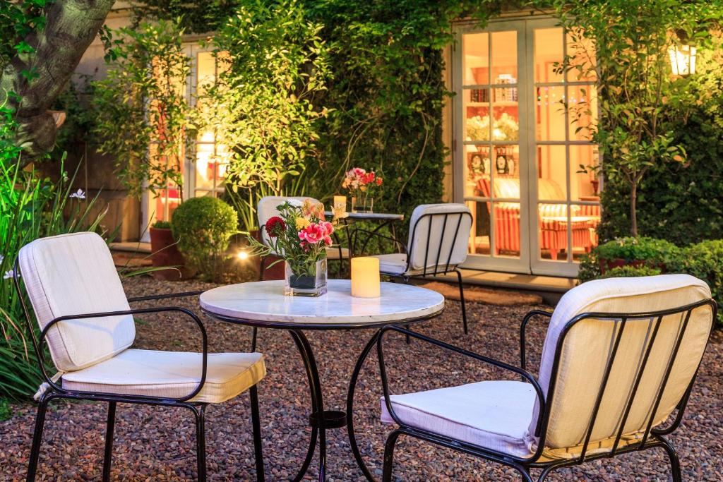 Área de lazer do Hotel Boutique Le Reve com uma mesa redonda a frente com duas cadeira e ao fundo outra mesa com duas cadeiras em volta de um jardim.
