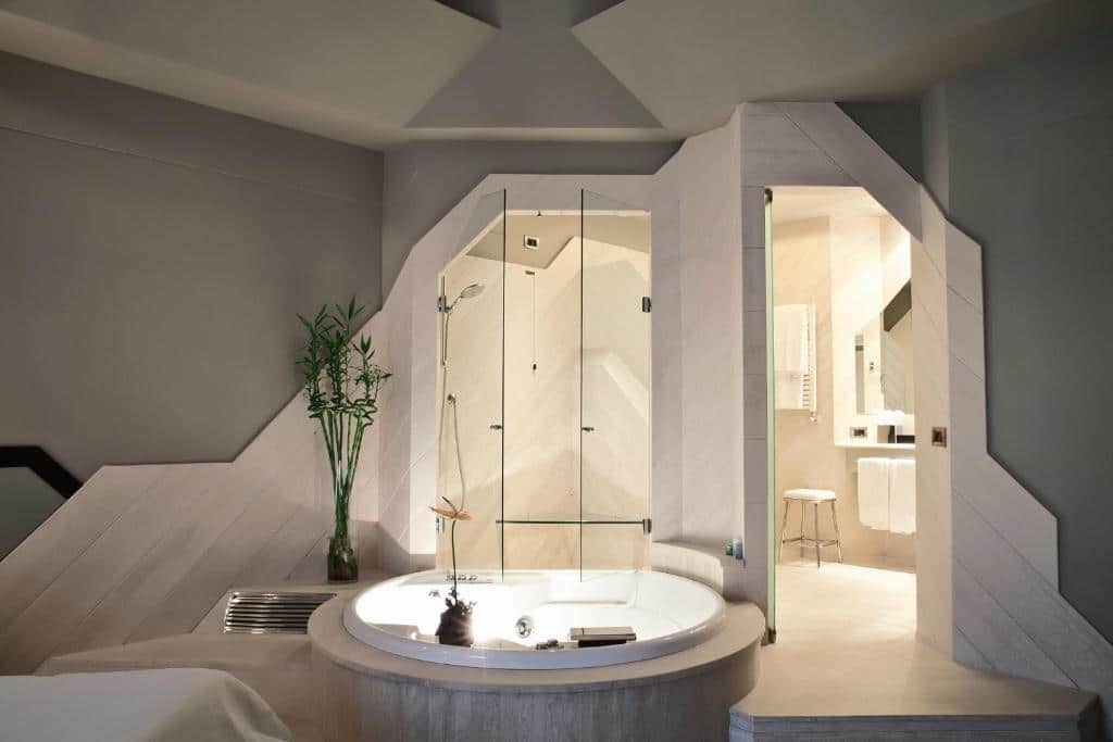 banheira de hidro em um banheiro especial e bastante amplo, com cadeira e barras de apoio atrás no Hotel Isa