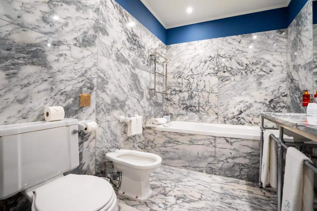 Banheiro do Grande Hotel do Porto com banheira de hidromassagem ao fundo, pia do lado direito e do lado esquerdo bidê e vaso sanitário.