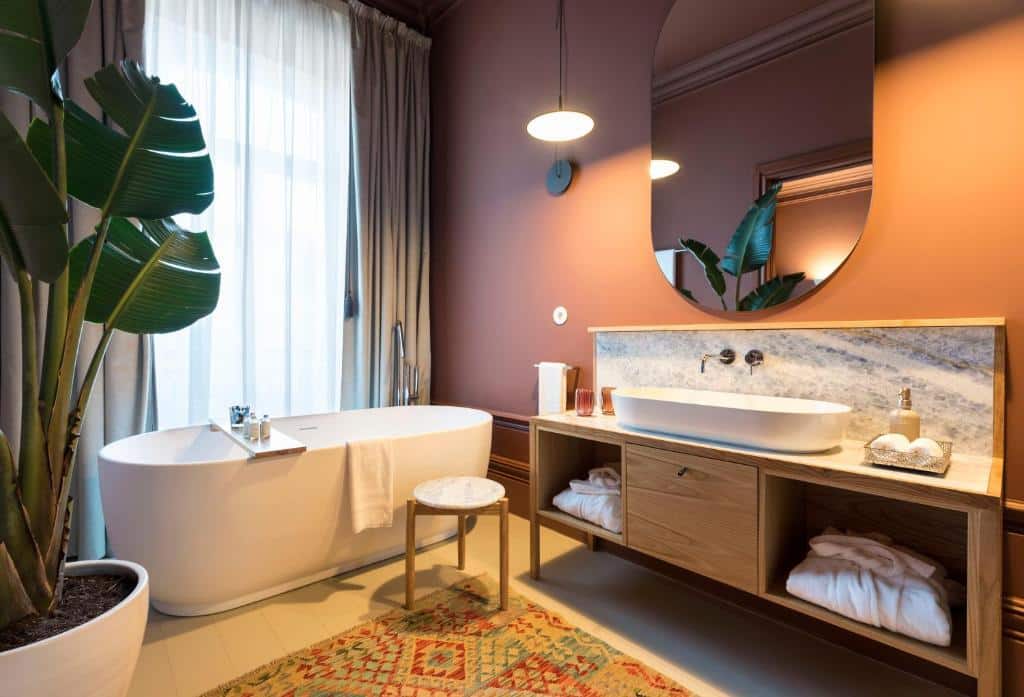 Banheiro do Jardins do Porto Boutique Guest House com banheira de hidromassagem do lado esquerdo e uma pia grande com espelho do lado direito.
