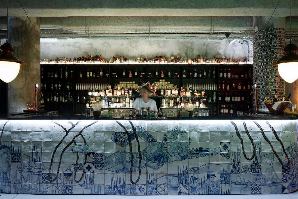 Bar do Zero Box Lodge Porto com balcão e ao fundo um funcionário e logo atrás as bebidas.