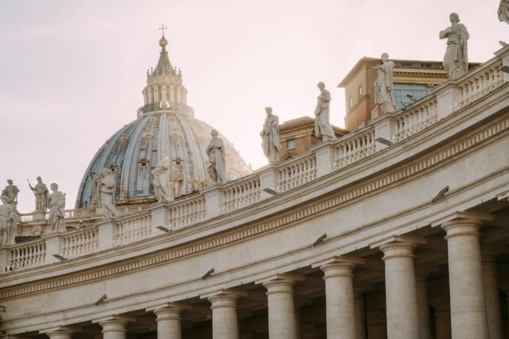 fachada da Basílica de São Pedro, no Vaticano, com colunas romanas, esculturas dos apóstolos e cúpula muito trabalhada em detalhes dourados