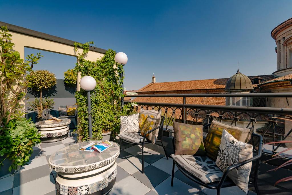Terraço do B&B Hotel Milano Sant'Ambrogio com diversas cadeiras com almofadas, vasos de plantas, postes de iluminação e um mesa de centro, para representar hotéis Ibis em Milão