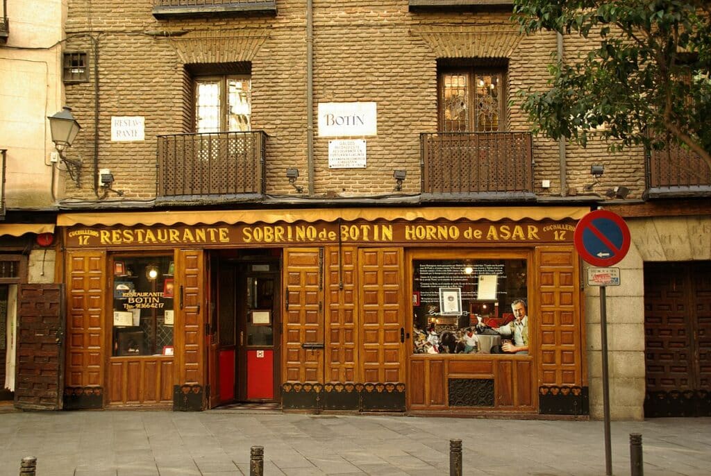 Fachada do restaurante Sobrino de Botín, uma das recomendações de Onde comer em Madri. A entrada é toda de madeira e há inscrições nas janelas. O nome do local está no topo, e há janelas com sacada logo acima. - Foto: Concepcion AMAT ORTA via Wikimedia Commons