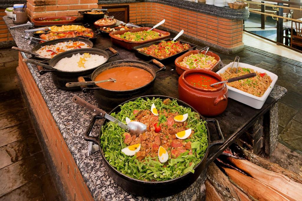 Buffet de almoço do Hotel Fazenda Campo dos Sonhos, em Socorro. Vemos várias opções de comidas muito coloridas e molhos, dispostos sobre uma mesa de mármore.