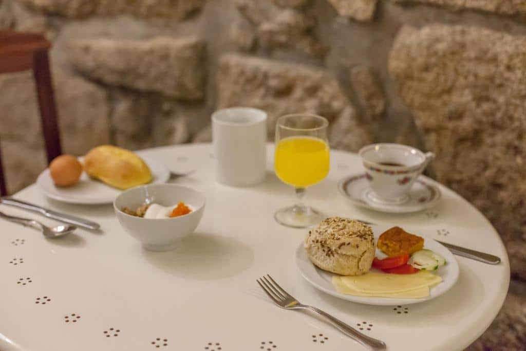 Café da manhã do Being Porto Hostel com suco, café, bolo e pão.