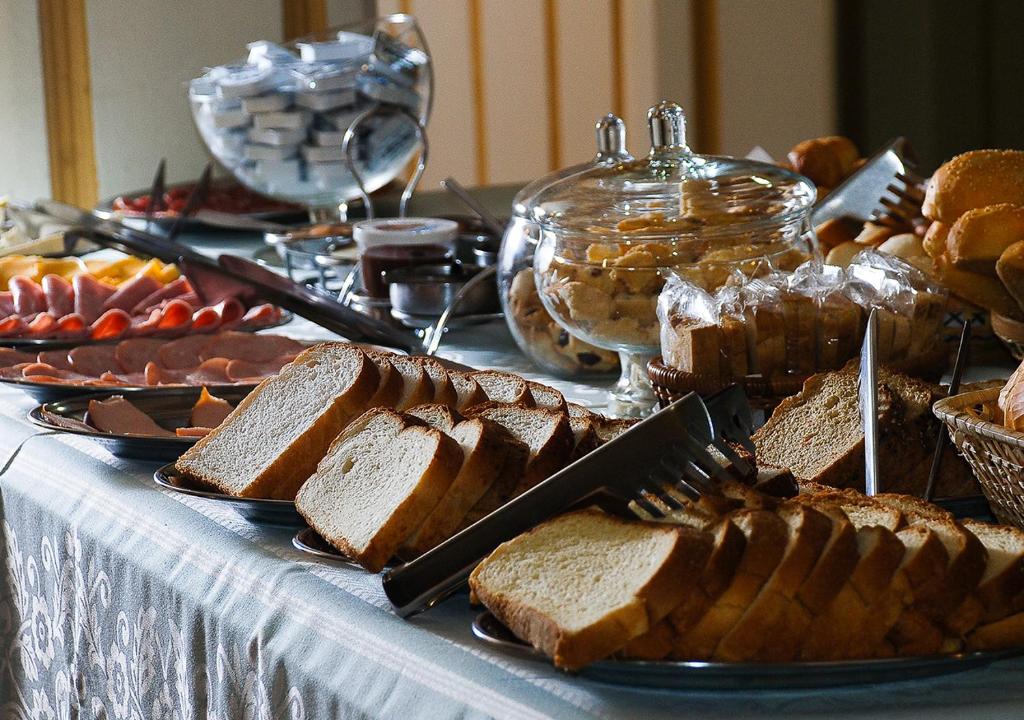Foto da mesa de café da manhã do Mirágua Refugios Pousada, em Brotas. É possível ver vários pães, torradas, frios, etc.