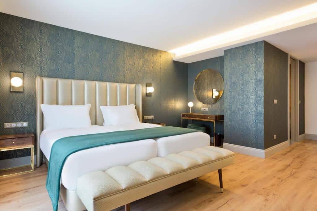 Quarto do Acta The Avenue com cama de casal do lado esquerdo com um banco estofado ao pé da cama.  Representa hotéis Mercure no Porto.