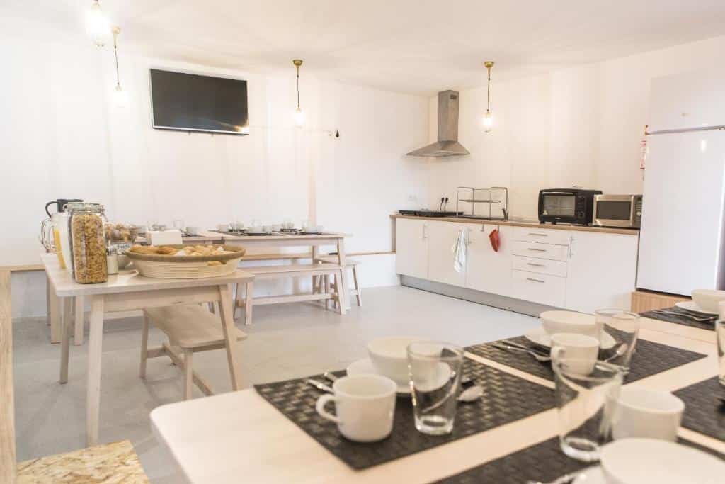 Cozinha do Porto Republica Hostel & Suites com armários, geladeira e fogão do lado direito do lado esquerdo uma mesa de madeira.