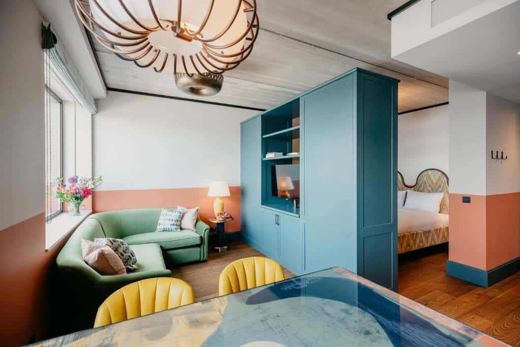 Estúdio do Hotel BOAT & CO, de 34 m², com sala de estar com sofá, uma mesa com cadeiras, e um guarda-roupa separando a cama de casal. Representa hotéis para família em Amsterdam