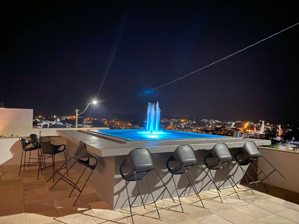 Chafariz iluminado de azul, com banquetas ao redor, na área externa do Dall'Onder Ski Hotel