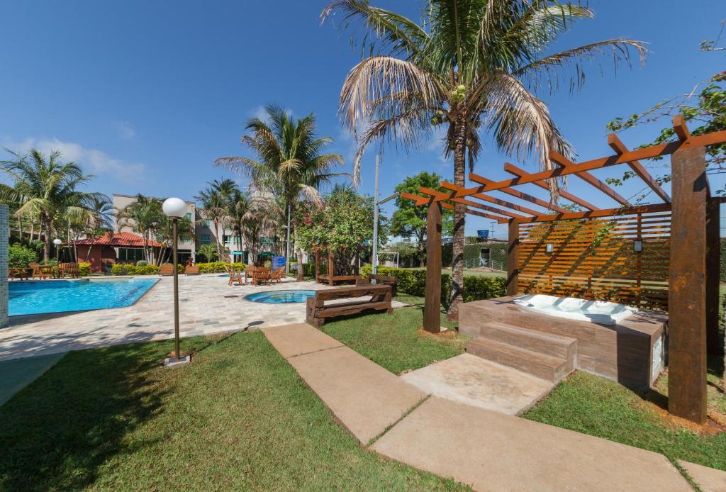 Área de fora do hotel com bastante árvores, gramado verde e piscinas azuis durante o dia, ilustrando post Hotéis em Maringá.