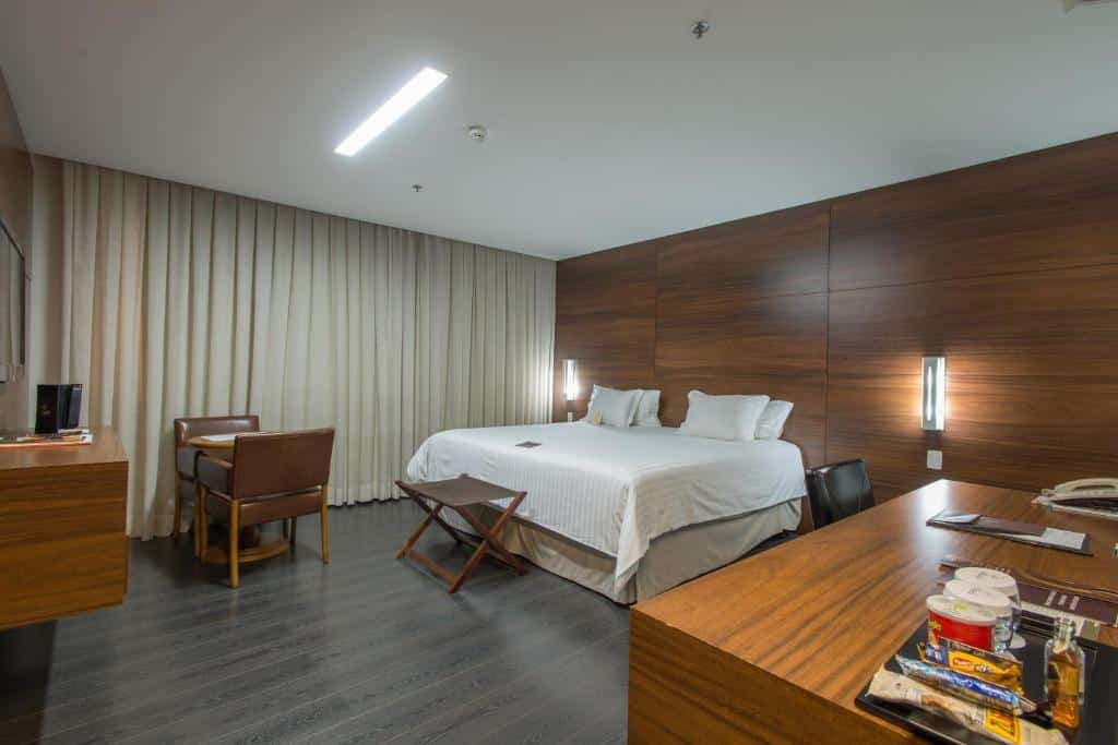 Quarto do Hotel Gran Odara com uma cama de casal, mesa de trabalho, mesa para dois e televisão. Foto para ilustrar post sobre hotéis em Cuiabá.