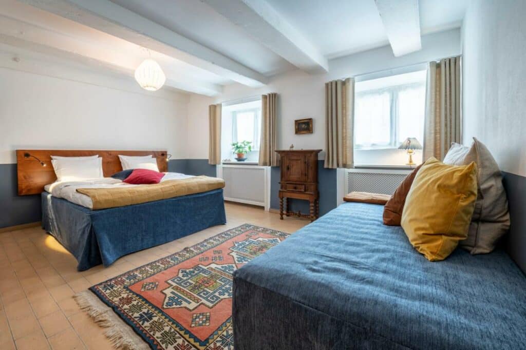 Quarto espaçoso do hotel Kanalhuset com duas camas, uma de casal e outra de solteiro. Há também duas janelas e um pequeno aemário. Foto para ilustrar post hotéis em Copenhague.