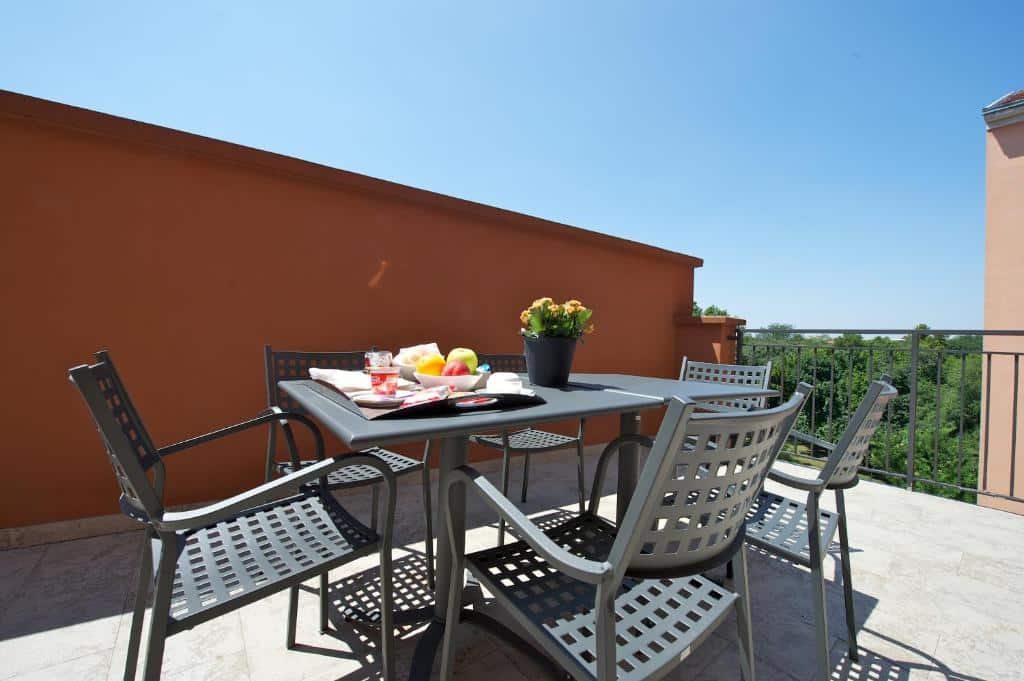 Terraço do Hotel Mercure Milano Solari com uma mesa com seis lugares, sob a mesa há um vaso de flor e uma bandeja com café da manhã, para representar hotéis Mercure em Milão