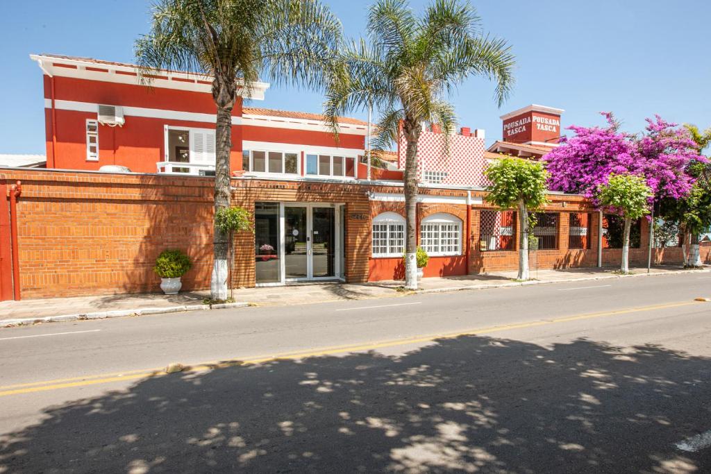 Vista externa do Hotel Pousada Casa Tasca, com paredes de tijolinhos e paredes pintadas de vermelho/laranja, em foto feita da rua da hospedagem