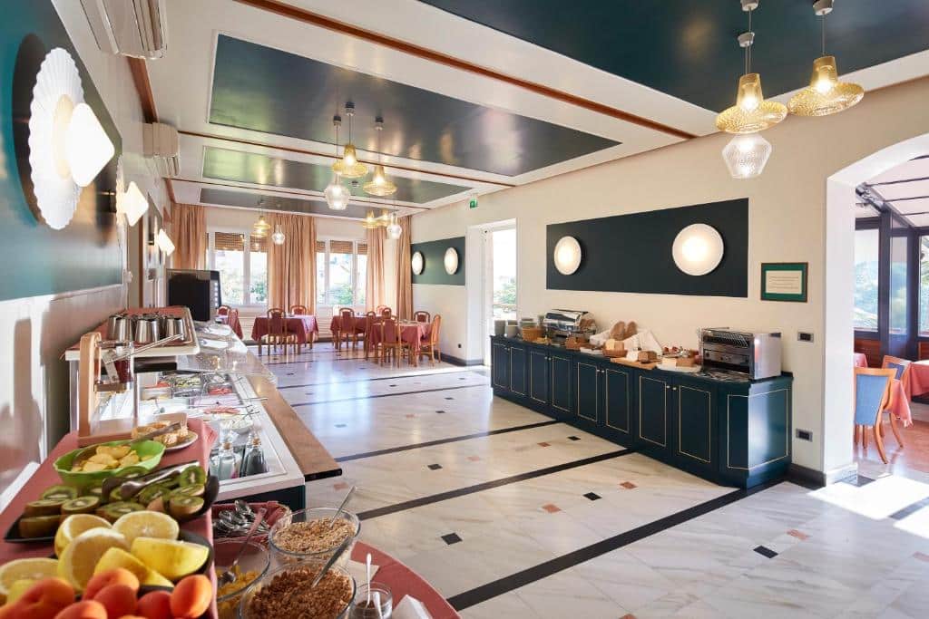 Parte do hotel com mesas para comer, móveis azuis escuro e uma bancada com frutas e outras comidas, ilustrando post Hotéis em Cinque Terre.