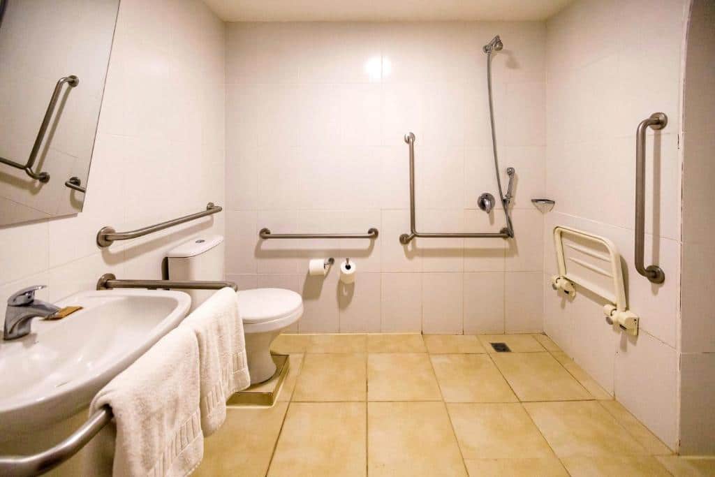 Banheiro do hotel Ibis Budget Maringa com barras de apoio na pia, no vaso sanitário e perto do chuveiro para ajudar pessoas com mobilidade reduzida, ilustrando post Hotéis em Maringá.