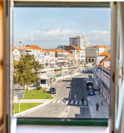 Janela de quarto de hotel com cortinas ao lado e vista para o canal central em Aveiro. Imagem para ilustrar o post hotéis em Aveiro.