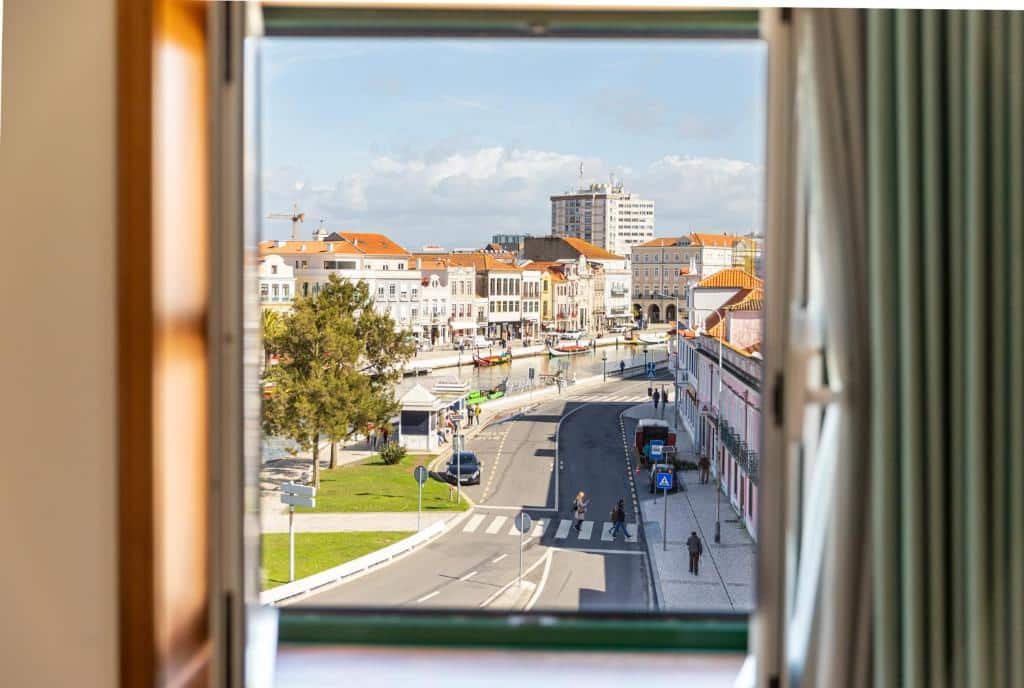 Janela de quarto de hotel com cortinas ao lado e vista para o canal central em Aveiro. Imagem para ilustrar o post hotéis em Aveiro.